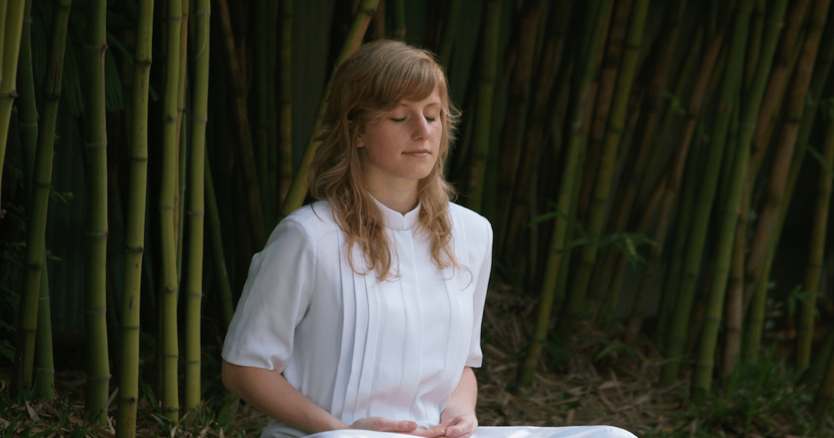 Woman in White Dress Meditating by Bamboo