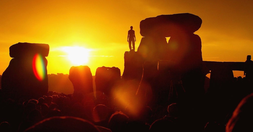 Person Standing on Large Canyon Rocks Facing the Sun