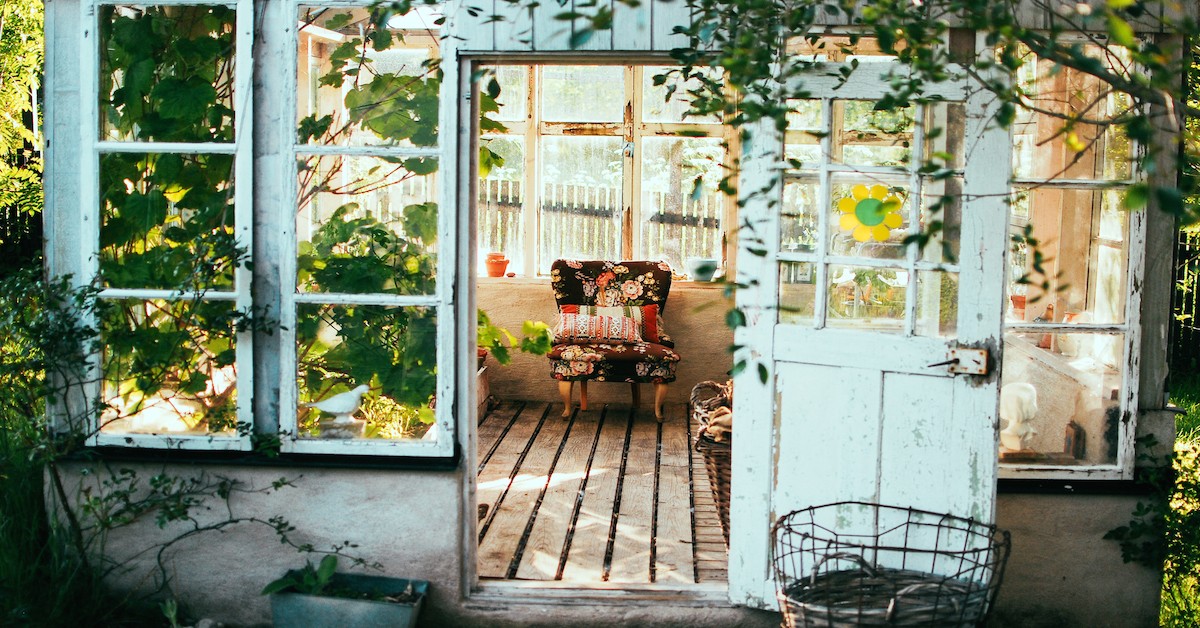 Rustic Sun Room with an Open Door and Filled with Plants and a Flowery Chair