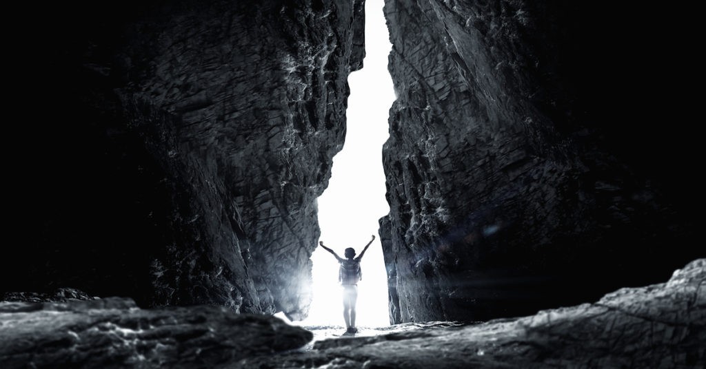 Child Raising Arms Facing the Light in a Dark Canyon