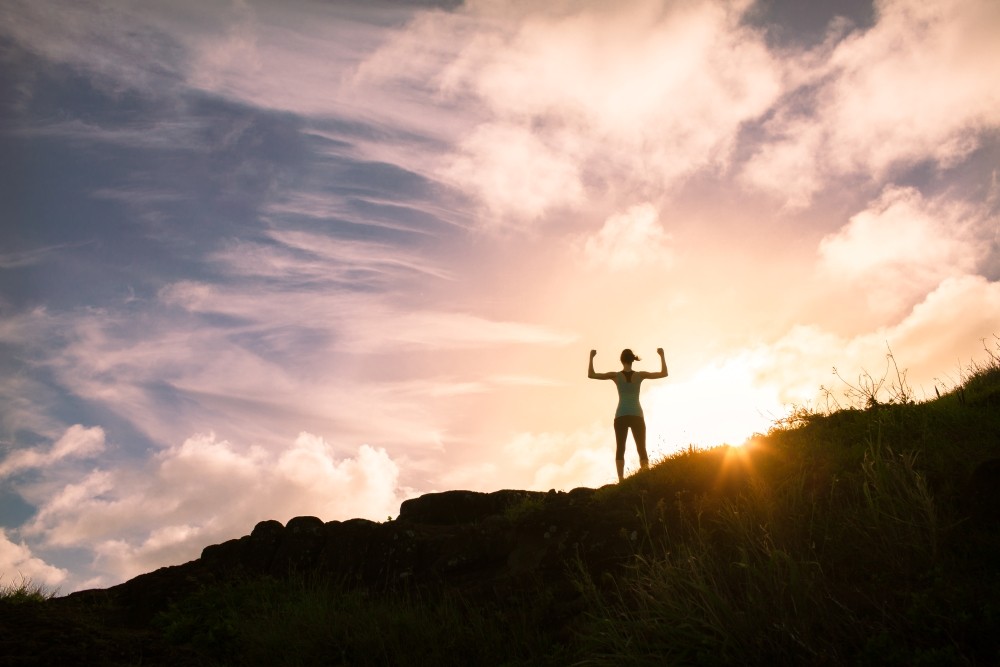 Woman on Top of a Mountain at Sunset