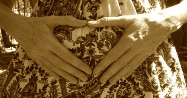 Woman's Hands Holding Womb Area on Flowery Dress