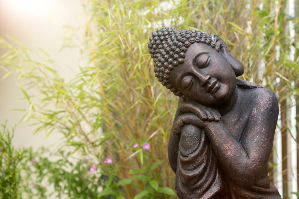 A Statue of Buddha Napping on One Knee, in Front of Bamboo