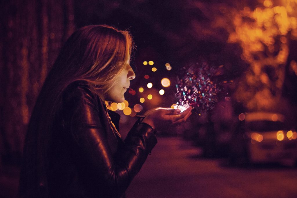 Woman Gently Blowing Into Her Own Glowing Cupped Hands