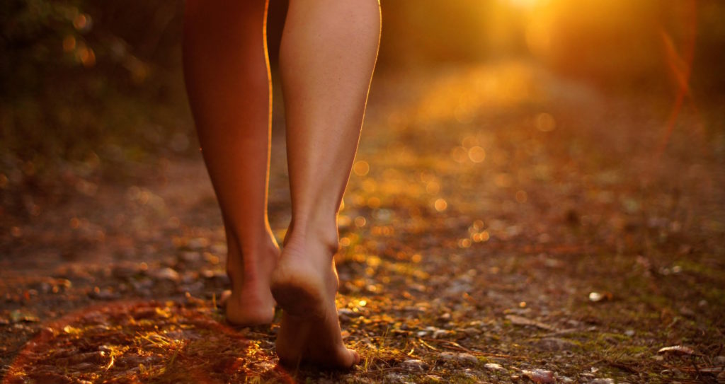 Person Walking Barefoot on Ground at Sunrise
