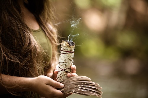 Young caucasian woman burning sage, practicing a purification ritual