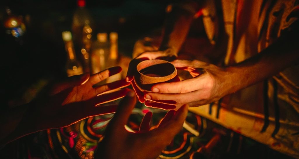 Person Offering a Cup of a Plant Medicine to Another Person